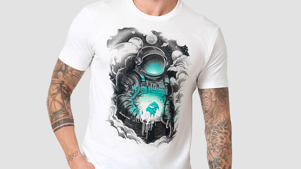 Man wearing a white graphic tee with a teal and black astronaut print, from INTO THE AM