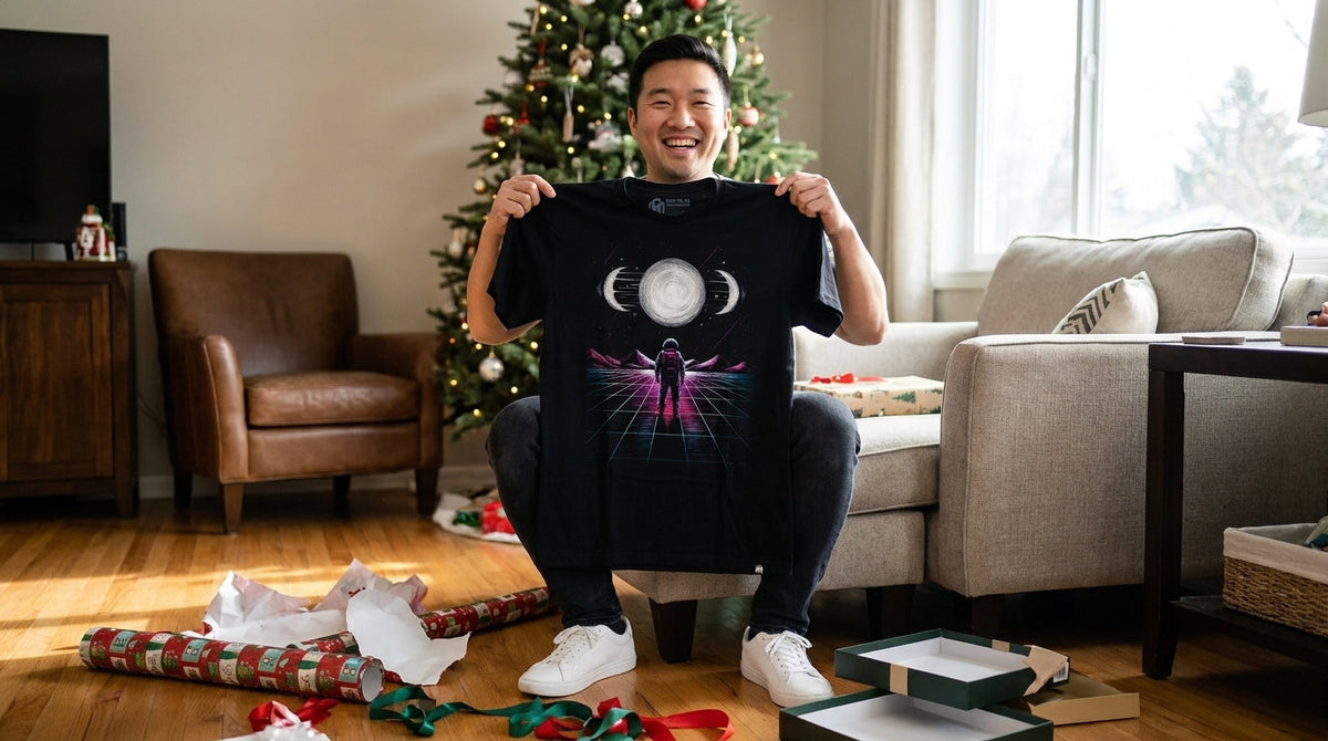 Man holding up the Celestial Pull graphic tee he just unwrapped on a holiday morning